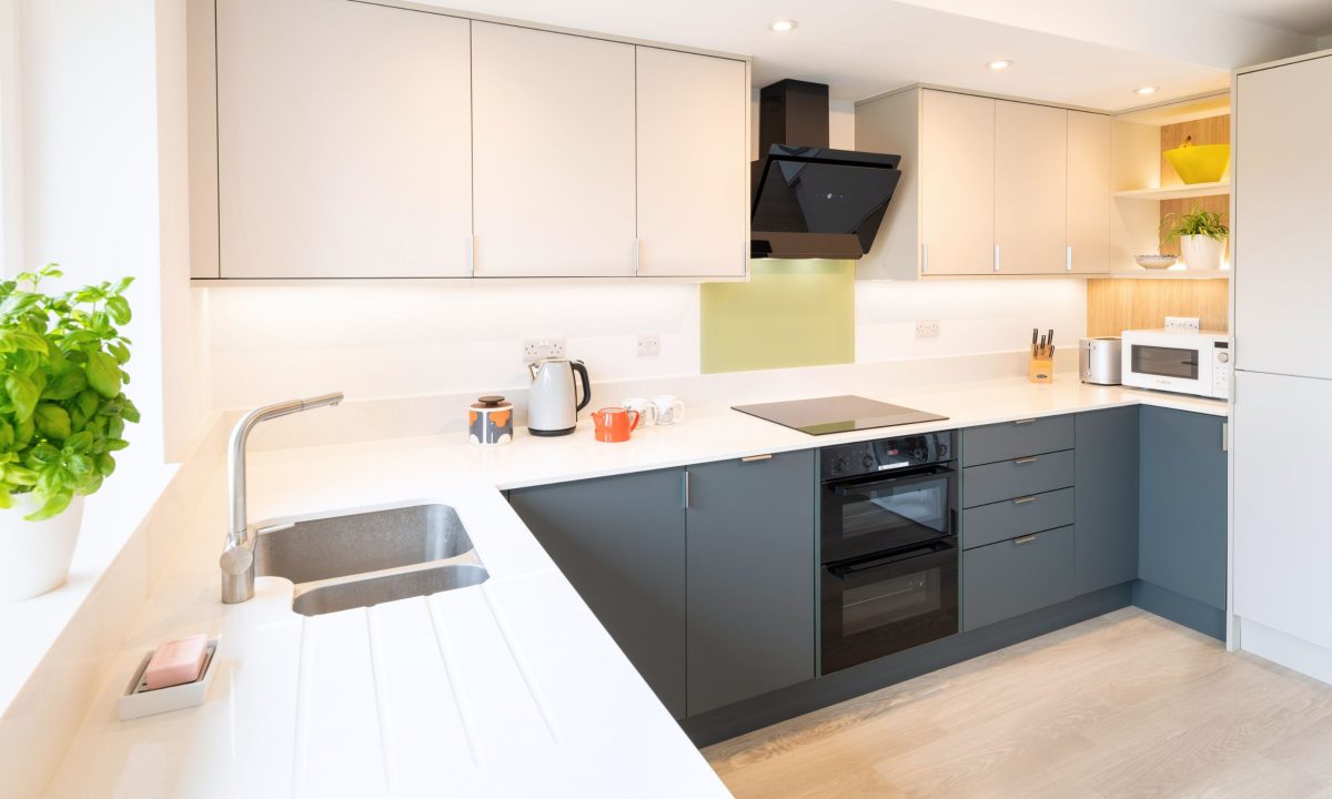 Compact modern kitchen with blue-grey cabinets, white worktops and integrated appliances