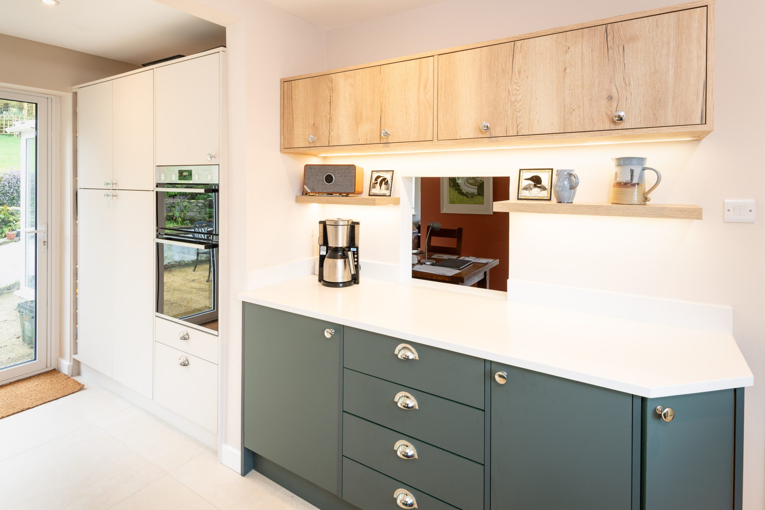 Shaker-style kitchen with sage green base units, white quartz worktop and light oak wall cabinets with under-cabinet lighting