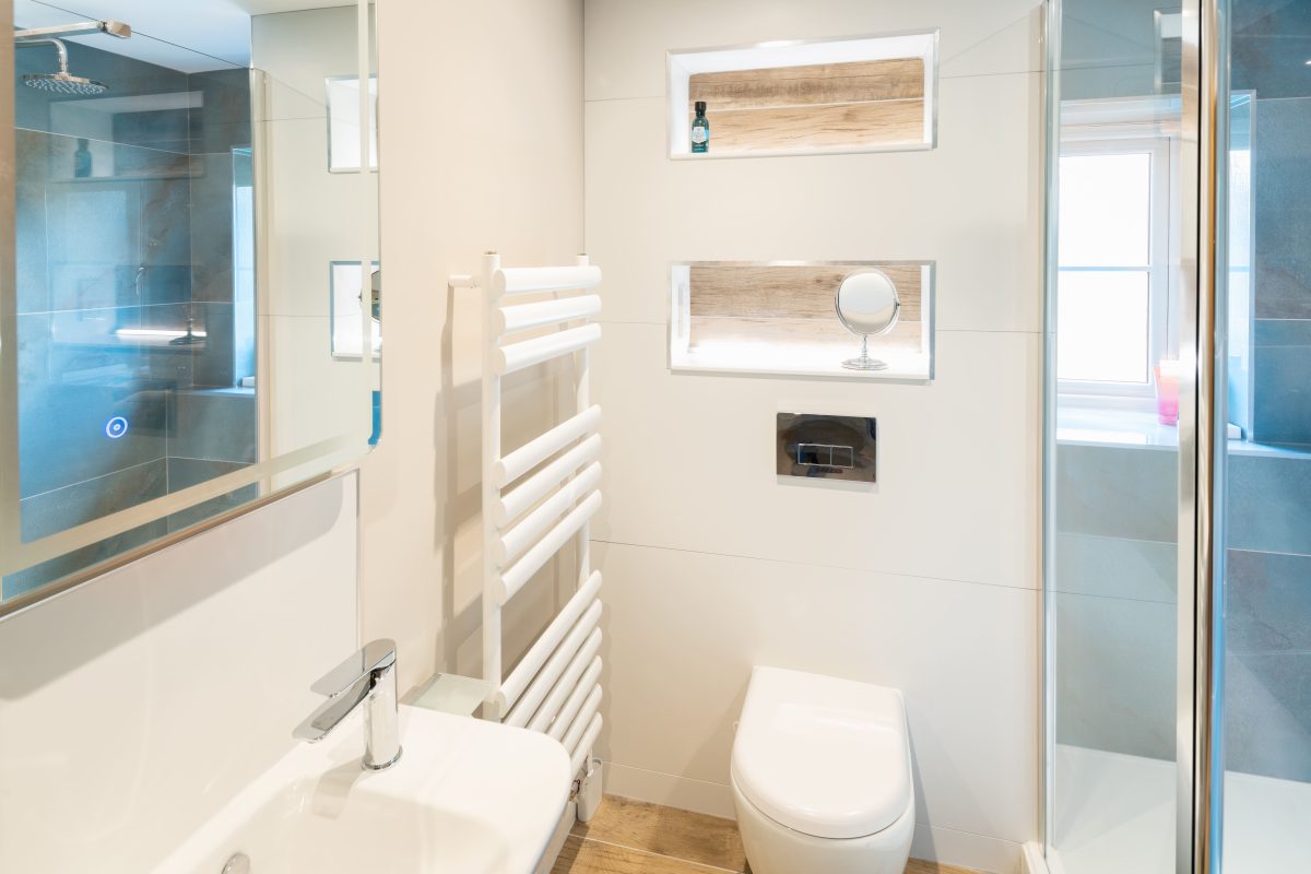Compact renovated bathroom with walk-in shower, wall-hung toilet and heated towel rail