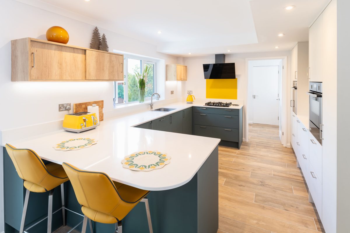 Contemporary galley kitchen with dark green island, white cabinets and yellow splashback